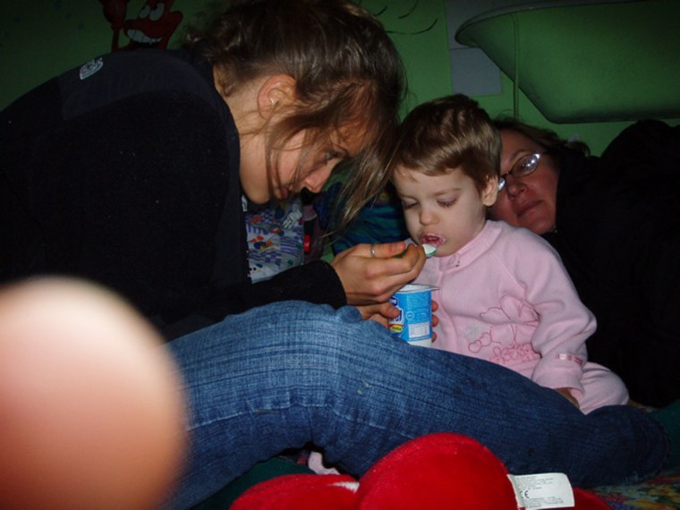 In this photo released by Global Volunteers, Emma Fisher feeds a girl named Ana-Maria while volunteering at Tutova Hospital's Failure to Thrive Clinic in Tutova, Romania,January 2006. AP Photo/Lilly Fisher)